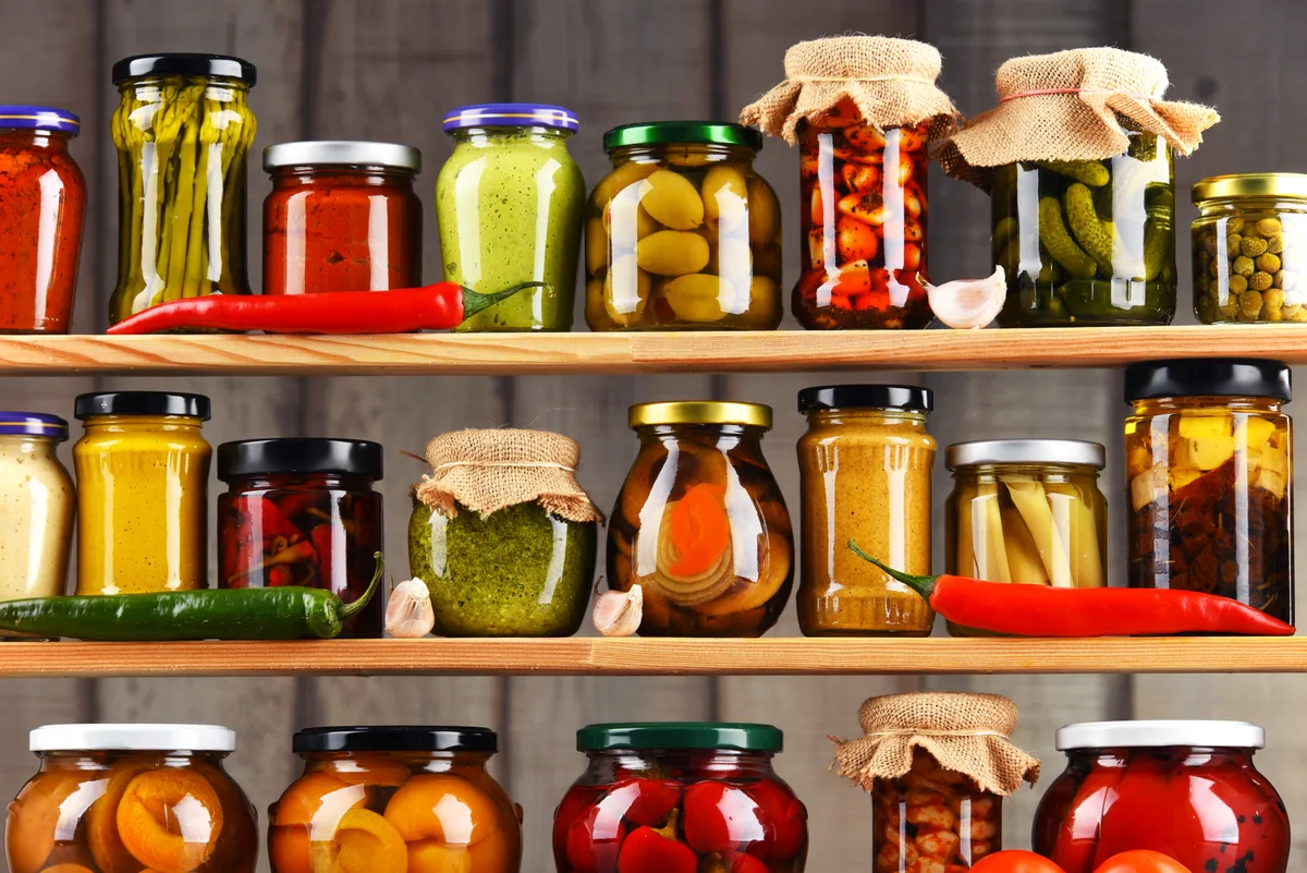 Jars of preserved Levantine condiments on a pantry shelf